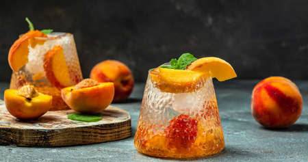 Refreshing Peach Bourbon Smash Cocktail with ice cubes, and mint in glass. Long banner format.の写真素材