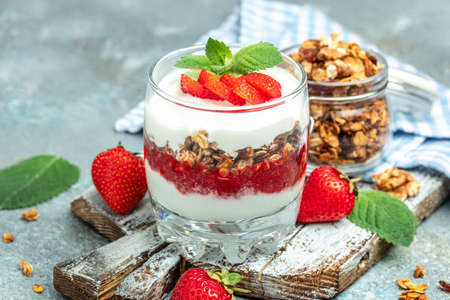 Parfait Greek yogurt with fresh strawberry and granola on a wooden board. gluten free diet, healthy breakfast. banner, menu, recipe place for text, top view,の写真素材