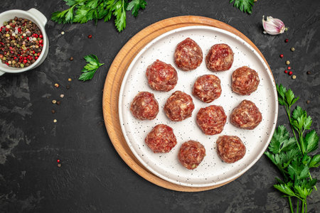 raw meatballs on wooden board, minced pork meat with spices on a dark background. Food recipe background. close up.の写真素材