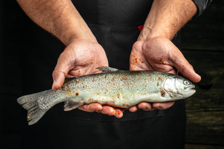 hands holding rainbow trout with spicesの写真素材