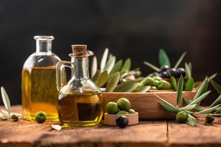 Olive oil in bottles with black and green olives and leaves. extra virgin olive oil jars on a wooden background. place for text.の写真素材