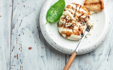 Burrata cheese with Basil leaves on white plate on light background. Long banner format. top view.の写真素材