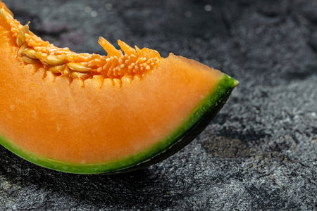 Raw Organic Tuscan Melon Cantaloupe. Yellow pieces of melon on a wooden board on a dark background, banner, menu, recipe place for text, top view,の写真素材