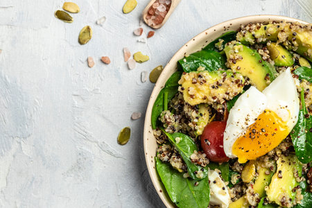 Keto diet plate quinoa, avocado, egg, tomatoes, spinach and sunflower seeds on light background. Healthy food, ketogenic diet, diet lunch concept, place for text, top view.の写真素材