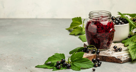 Jar of delicious homemade black currant curd, custard or jam and fresh berries on gray concrete background. Long banner format. top view,の写真素材