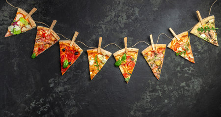 Different pieces of pizza on a string with clothespins dark background. Long banner format. top view,の写真素材