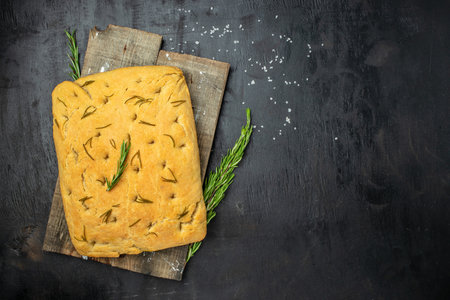 foccacia bread. olive oil and herbs on a dark background. banner, menu, recipe place for text, top view.の写真素材
