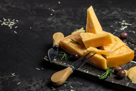 Parmesan cheese on a wooden board, Hard cheese on a dark background. top view.の写真素材