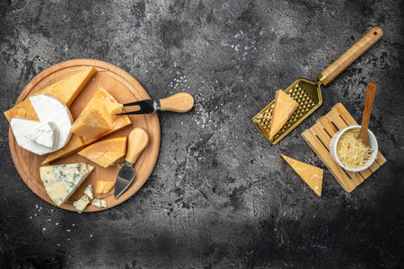 Piece of Parmesan cheese and assortment of different cheeses dor blu, camamber brie with knife on a dark background. Long banner format. top view.の写真素材