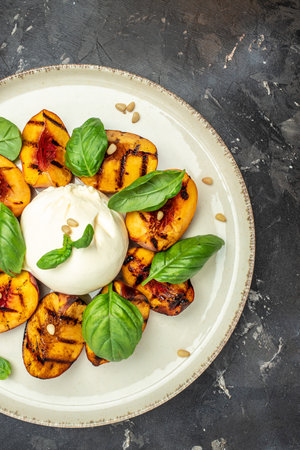 Burrata soft cheese and grilled peaches with basil and pine nuts, drizzled honey, Food recipe background. close up,の写真素材