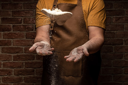 flying pizza dough with flour scattering in a freeze motion of a cloud of flour midair on black. Cook hands kneading dough. copyspace.の写真素材
