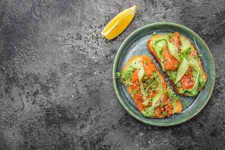 two toasts with salted salmon, guacamole avocado and fresh greens on plate. superfood concept. Healthy, clean eating. Vegan or gluten free diet. top view.の写真素材