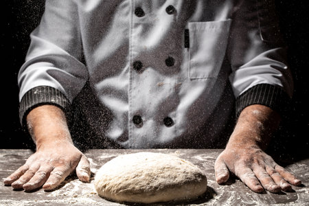 Beautiful and strong men's hands knead the dough from which they will then make bread, pasta or...