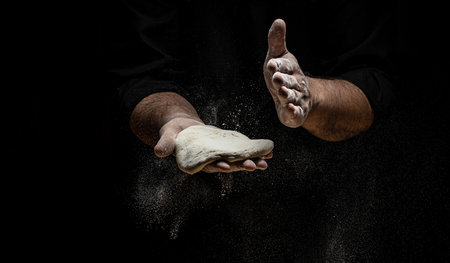 Clap hands of baker with flour. Beautiful and strong men's hands knead the dough make bread, pasta or pizza. Powdery flour flying into the air. Long banner format.の写真素材