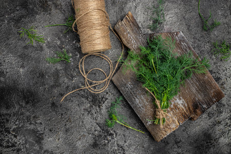 bunch of fresh organic dill on a cutting board on dark background. Long banner format. top view.の写真素材