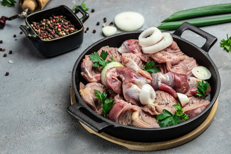 Raw uncooked chicken gizzards, stomach on a slate board. Traditional Korean spicy chicken meat. Long...