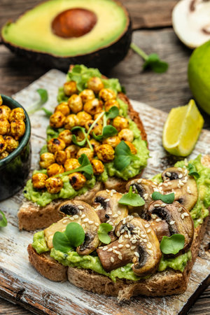 Healthy avocado toasts with chickpeas and mushrooms on a wooden background, vegetarian vegan food. vertical image. top view. place for text.の写真素材