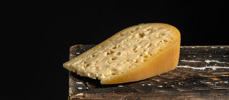 french hard cheese with holes emmentaler on a dark background. Long banner format.の写真素材