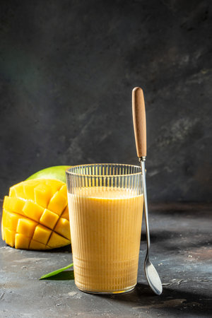 Healthy mango smoothie in a glass. Indian healthy ayurvedic cold drink with mango, Delicious breakfast or snack, vertical image. place for text.の写真素材