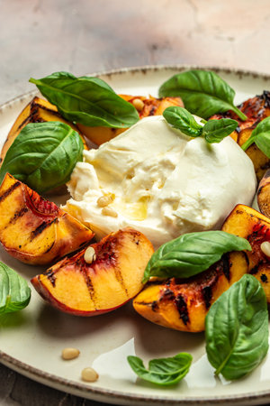 Burrata soft cheese and grilled peaches with basil and pine nuts, drizzled honey, Food recipe background. close up,の写真素材