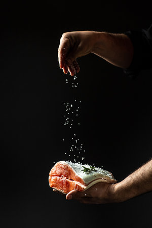 The chef prepares fresh fish salmon, trout, sprinkles with sea salt in a freeze motion. chef...