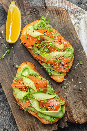 two toasts with salted salmon, guacamole avocado and fresh greens on plate. superfood concept. Healthy, clean eating. Vegan or gluten free diet. top view.の写真素材