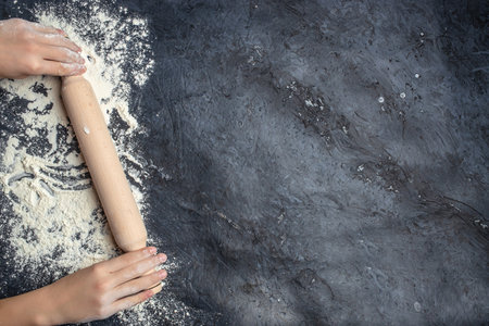 hands keep rolling pin with flour on a dark background. baking background, banner, menu, recipe place for text, top view.の写真素材