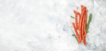 Long thin dry sausages. spicy pork fermented dry cured sausages on a light background. Long banner...