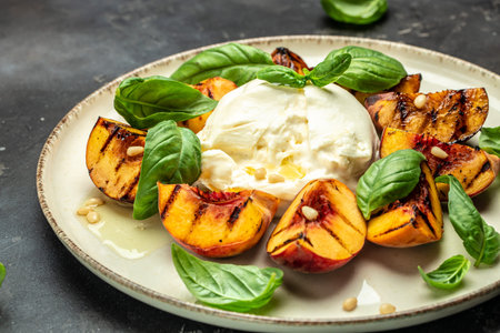 Burrata soft cheese and grilled peaches with basil and pine nuts, drizzled honey, Food recipe background. close up,の写真素材