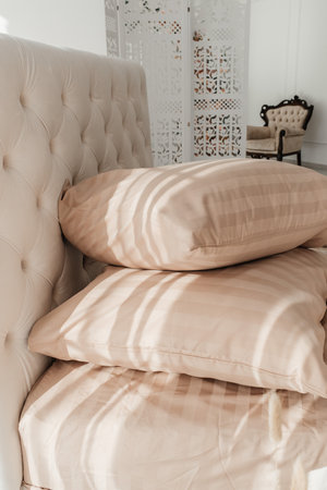 Close up view of hypoallergenic pillow in pillowcase over natural gray linen sheets in bedroom. Cotton bedding lying on comfortable bed.の写真素材