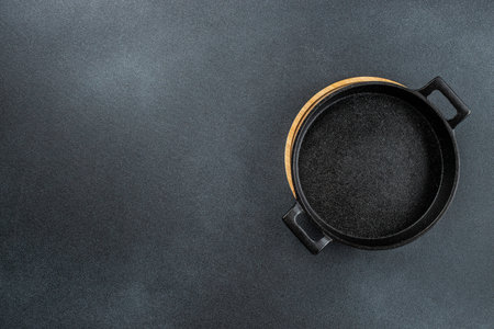Empty cast iron frying pan on dark concrete background. food cooking background. top view.