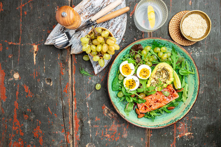 Salted salmon salad with fresh green lettuce, grapes, eggs and avocado. Ketogenic, keto or paleo diet lunch bowl. top view.の写真素材