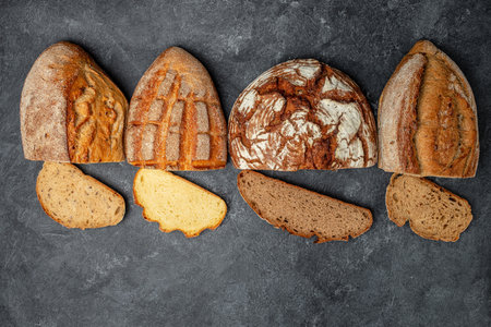 Slices of Craft bread. homemade bakery. Different kinds of bread on a dark background. Long banner format.の写真素材