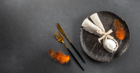 Easter table setting with plate, fork and knife, Easter eggs, bunny decor on a dark background,...