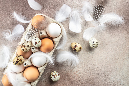 Chicken and quail eggs with feathers on light background. top view.の写真素材