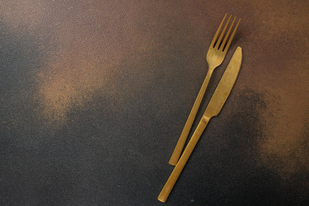 Golden Knife and fork for a festive table for a wedding, birthday or party on a dark background. place for text, top view,の写真素材