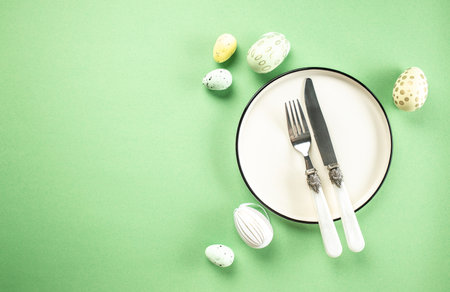 table setting. A plate with Easter eggs on green background. Happy Easter holiday concept.