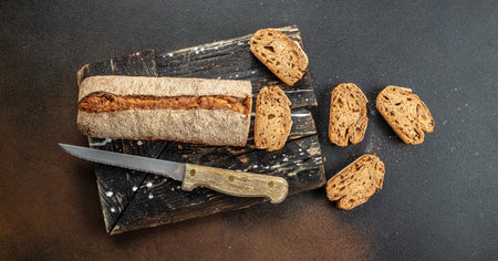 French baguette bread sliced on dark concrete background, Long banner format. top view.の写真素材