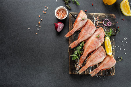 Fish raw snapper with lemon, rosemary, salt on a wooden board. banner, menu, recipe place for text,...