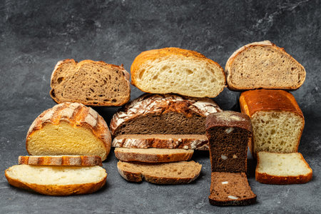 Slices of Craft bread. homemade bakery. Different kinds of bread on a dark background. Long banner...