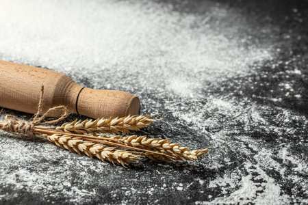 sprinkled wheat flour, grain and ears on dark background. banner, menu, recipe place for text, top view.の写真素材