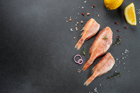 Raw fish perch with lemon, rosemary, salt on a dark background. banner, menu, recipe place for text,...