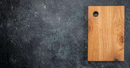 Chopping wooden board, seasonings and rosemary on dark background. Long banner format. top view.