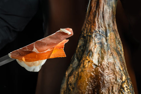 cutting specialist cortador holds Iberian ham Dry Spanish ham, Jamon Serrano, Bellota, Italian Prosciutto Crudo or Parma ham.の写真素材