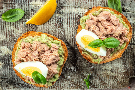 Tuna sandwiches with avocado and boiled egg on a wooden board. Food recipe background. close up.の写真素材