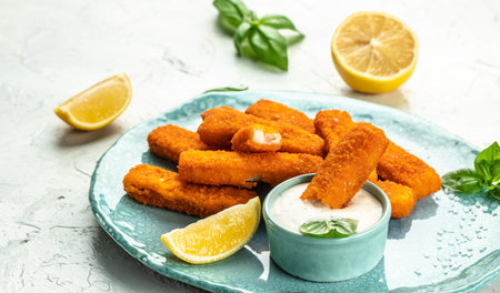 Crumbed fish sticks served with lemon and tartar sauce. Long banner format. top view.の写真素材