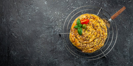 balkan pie. freshly baked filo pastry pie with meat on a dark background. Long banner format. top...
