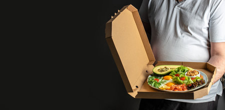 man hands holds Keto plate of healthy food in a pizza box. Concept of healthy eating or fast food. Long banner format.の写真素材