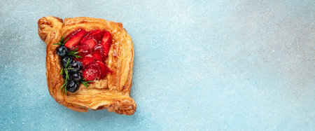 Fresh delicious puff pastries with sweet berries on a light background. Long banner format. top...