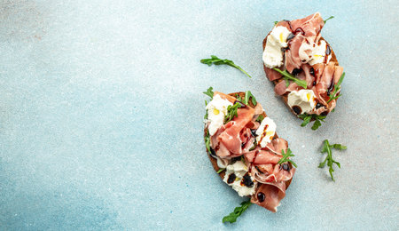 Toast with prosciutto and cream cheese on a blue background. Long banner format. top view.の写真素材